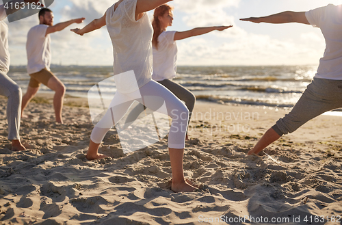 Image of group of people making yoga exercises on beach