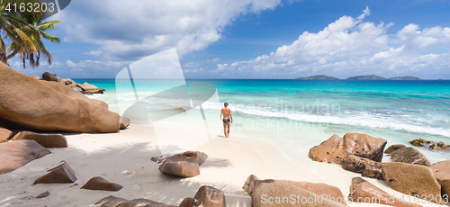 Image of Man enjoying Anse Patates picture perfect beach on La Digue Island, Seychelles.