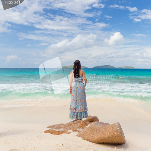 Image of Woman enjoying Anse Patates picture perfect beach on La Digue Island, Seychelles.