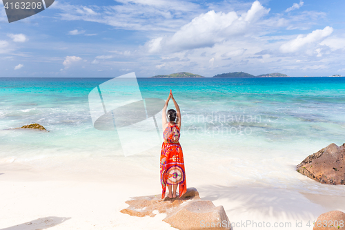 Image of Woman enjoying Anse Patates picture perfect beach on La Digue Island, Seychelles.