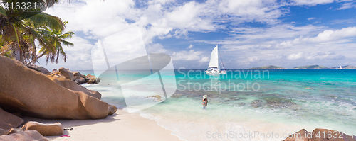 Image of Woman enjoying Anse Patates picture perfect beach on La Digue Island, Seychelles.