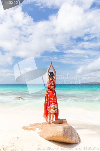 Image of Woman enjoying Anse Patates picture perfect beach on La Digue Island, Seychelles.