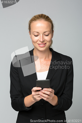 Image of Beautiful young caucasian businesswoman using mobile phone.