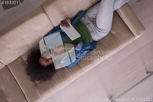 Image of african american woman at home with digital tablet top view