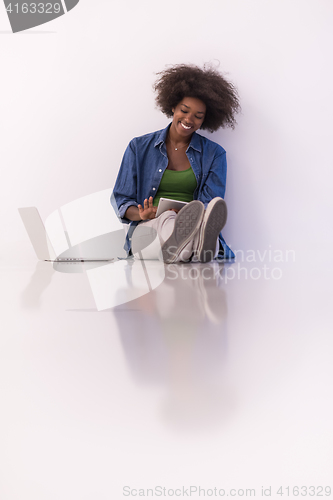 Image of african american woman sitting on floor with laptop