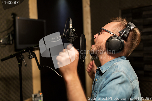 Image of man with headphones singing at recording studio