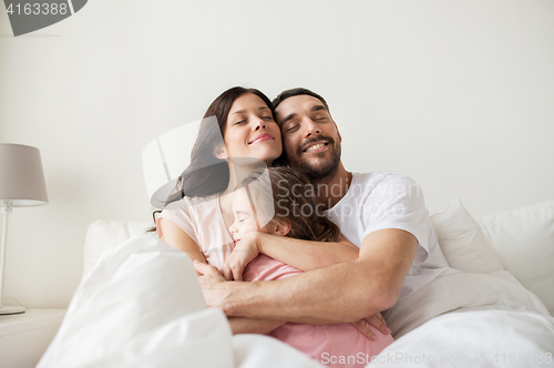 Image of happy family hugging in bed at home