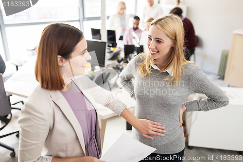 Image of happy colleague with pregnant woman at office