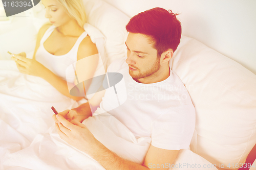 Image of couple with smartphones in bed