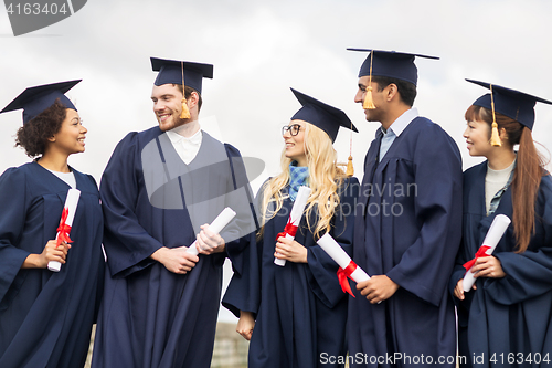 Image of happy students in mortar boards with diplomas