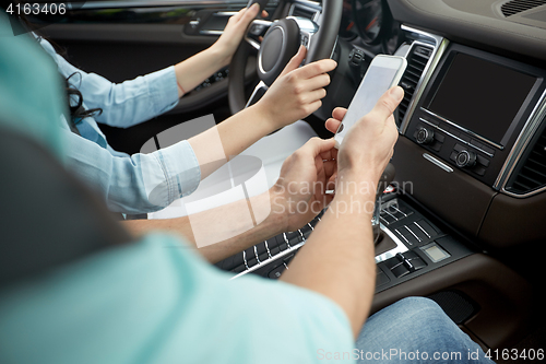 Image of happy man and woman with smartphone driving in car