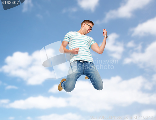 Image of happy man jumping and playing imaginary guitar