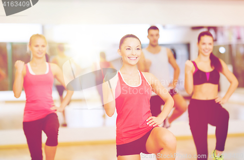 Image of group of smiling people exercising in the gym