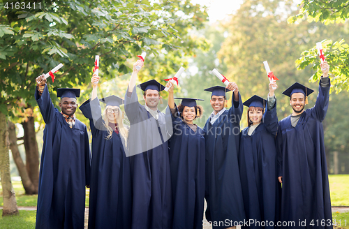 Image of happy students in mortar boards with diplomas