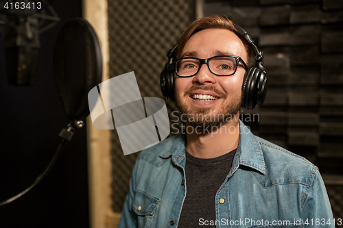 Image of man with headphones singing at recording studio