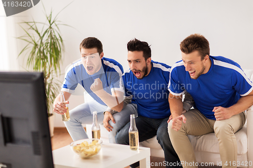 Image of friends or football fans watching soccer at home