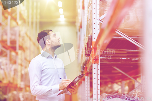 Image of businessman with clipboard at warehouse