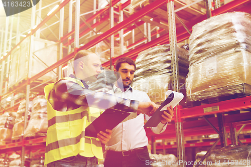 Image of worker and businessmen with clipboard at warehouse