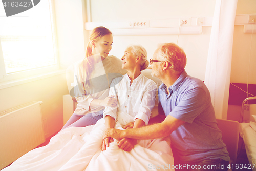 Image of happy family visiting senior woman at hospital