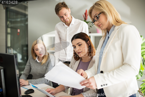 Image of happy creative team with papers in office