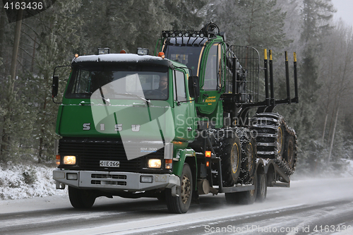 Image of Green SISU Truck Hauls John Deere Forwarder in Winter