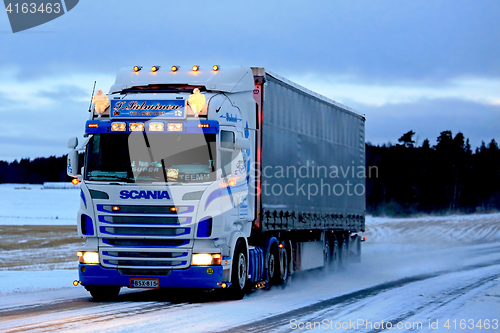 Image of Super Scania Semi on Snowy Road at Sunset