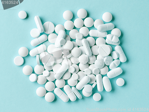 Image of various white pills on blue background