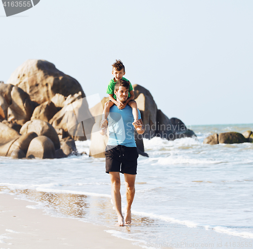 Image of happy family on beach playing, father with son walking sea coast