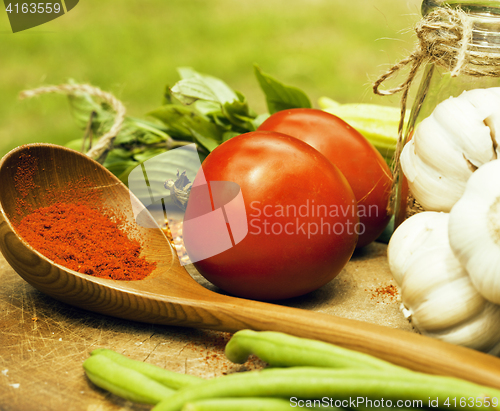 Image of vegetables on wooden kitchen with spicies, tomato, chilli, green