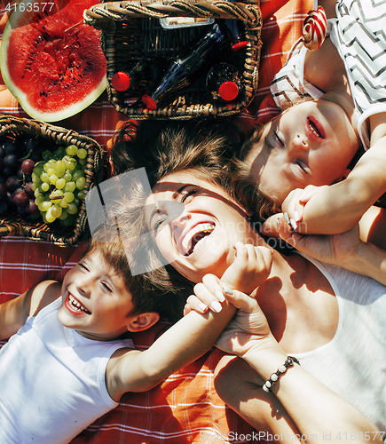 Image of cute happy family on picnic laying on green grass mother and kids, warm summer vacations close up, brother and sister 