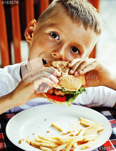 Image of little cute boy 6 years old with hamburger and french fries maki