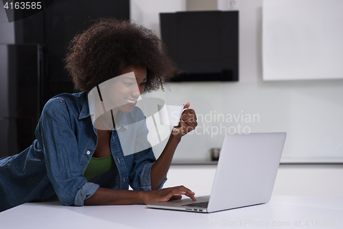 Image of smiling black woman in modern kitchen