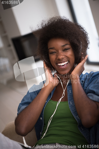 Image of African american woman at home in chair with tablet and head pho