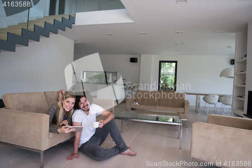 Image of couple relaxing at  home with tablet computers