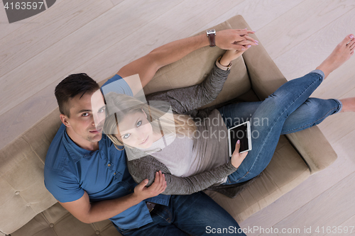 Image of youg couple in living room with tablet top view