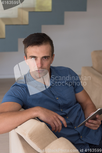 Image of young man using a tablet at home