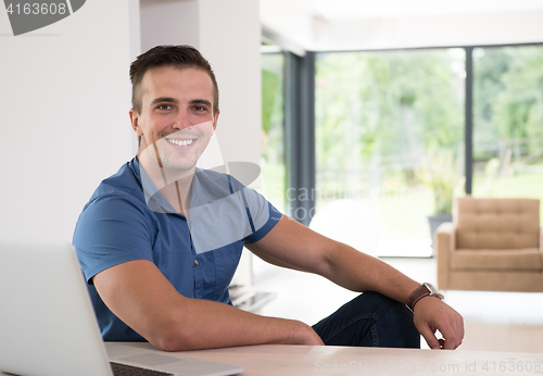 Image of Young man with laptop at home