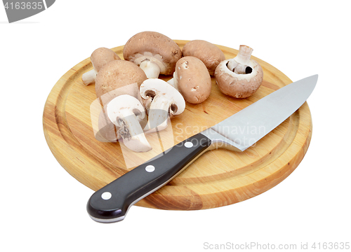Image of Whole and halved chestnut mushrooms on board with knife