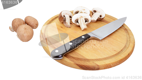 Image of Chestnut mushrooms with sliced halves on wooden board with knife