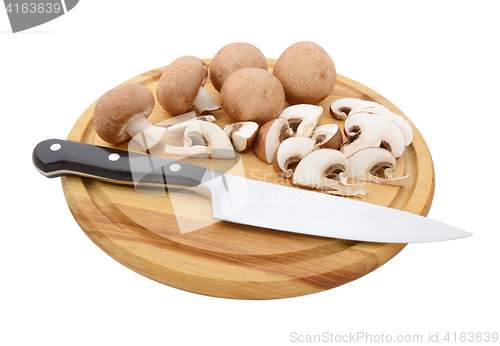 Image of Whole and sliced chestnut mushrooms on board with knife