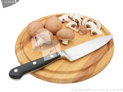 Image of Knife with whole chestnut mushrooms and slices on board