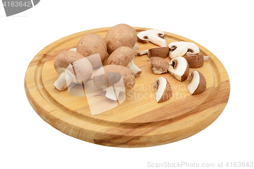 Image of Whole and sliced chestnut mushrooms on a wooden cutting board