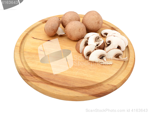 Image of Sliced and whole chestnut mushrooms on a wooden cutting board