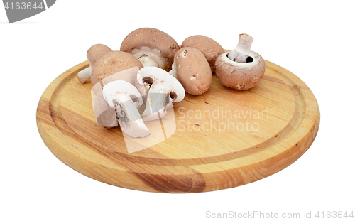 Image of Chestnut mushrooms, whole and halved on a wooden board