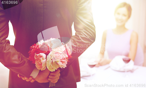 Image of close up of man hiding flowers behind from woman