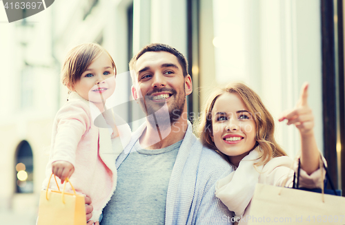 Image of happy family with child and shopping bags in city