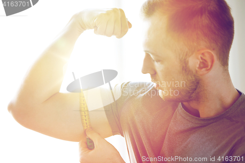 Image of close up of male hands with tape measuring bicep