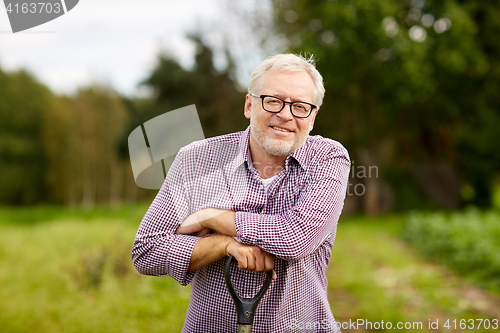 Image of happy smiling senior man with garden tool at farm