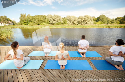 Image of group of people making yoga exercises outdoors