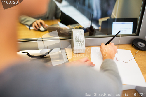 Image of customer writing application at bank office